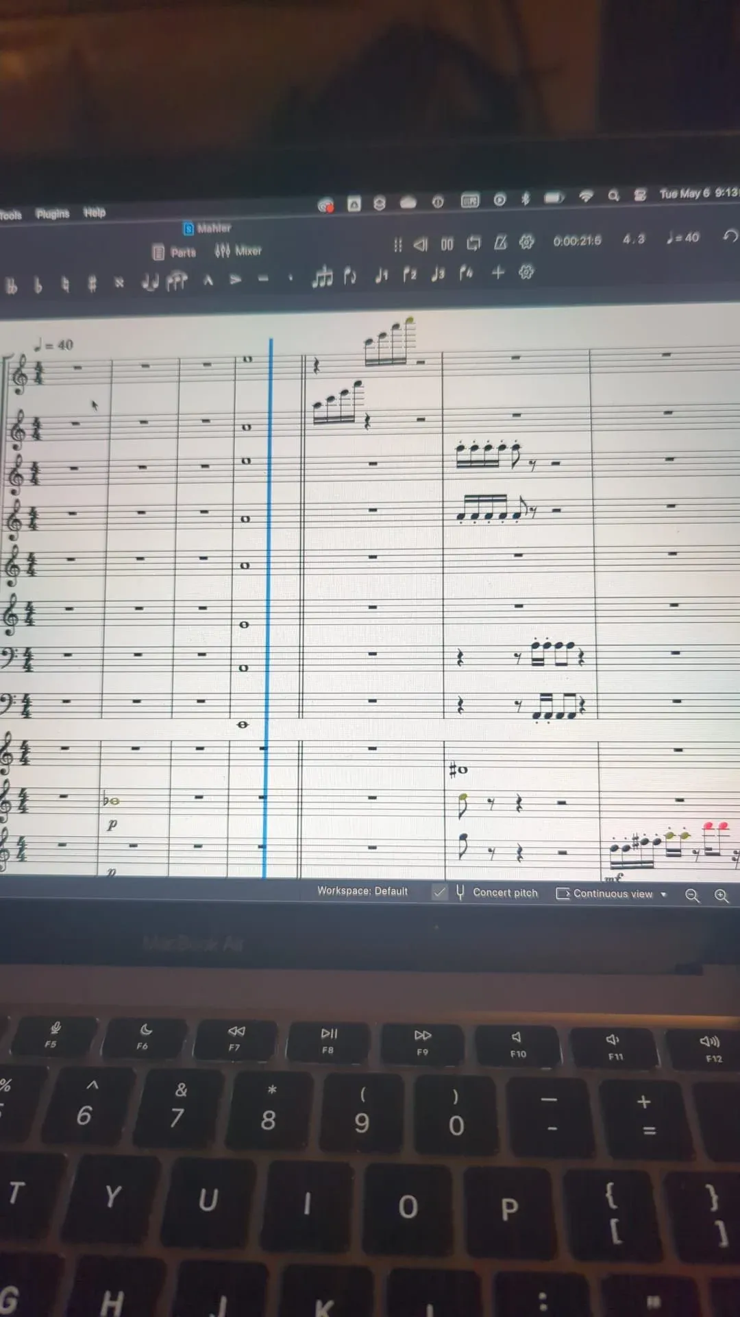 A laptop screen filled with notation software, an orchestral score open across the staves.