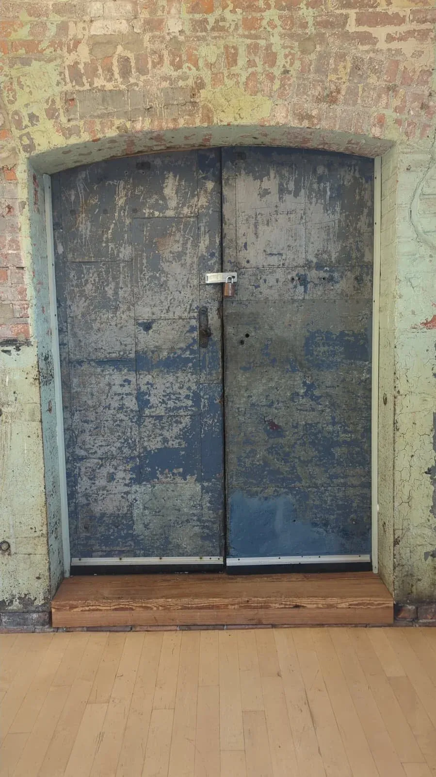 A weathered blue-painted double door set into a rough stone wall.