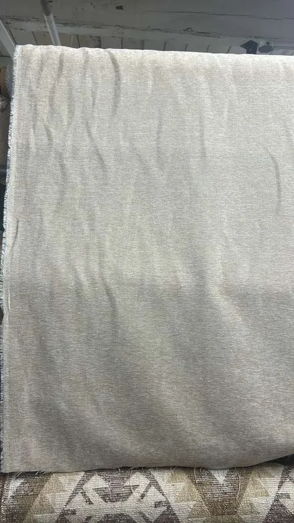 A length of undyed linen hung over a rail against a white wall.